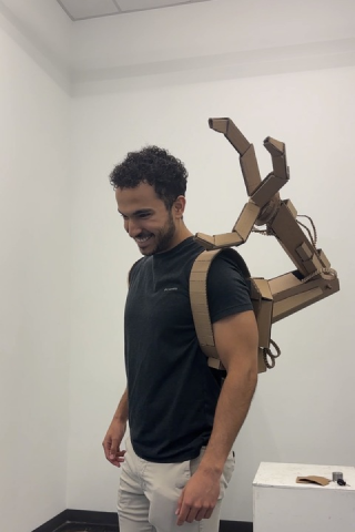 Michael Sezen with a cardboard scultpure of a robotic third arm attached to his back