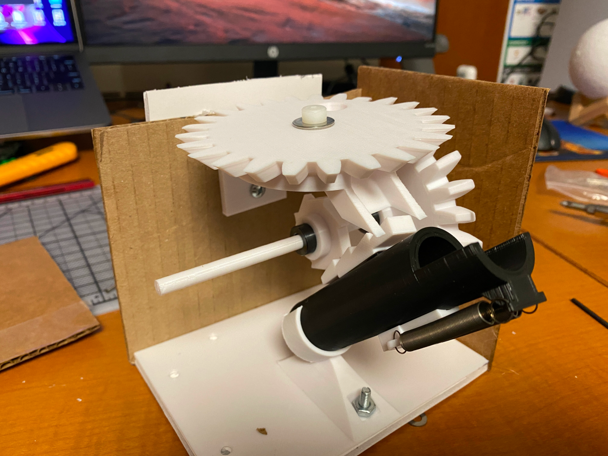 3D printed gears and cannon assembled inside a carboard frame