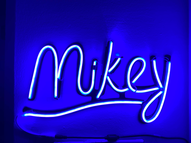 A bright neon-like sign with 'Mikey' drawn with the lights