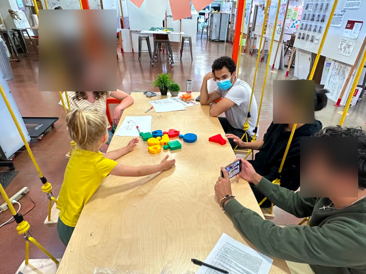 Four students observing young child playing with toyset